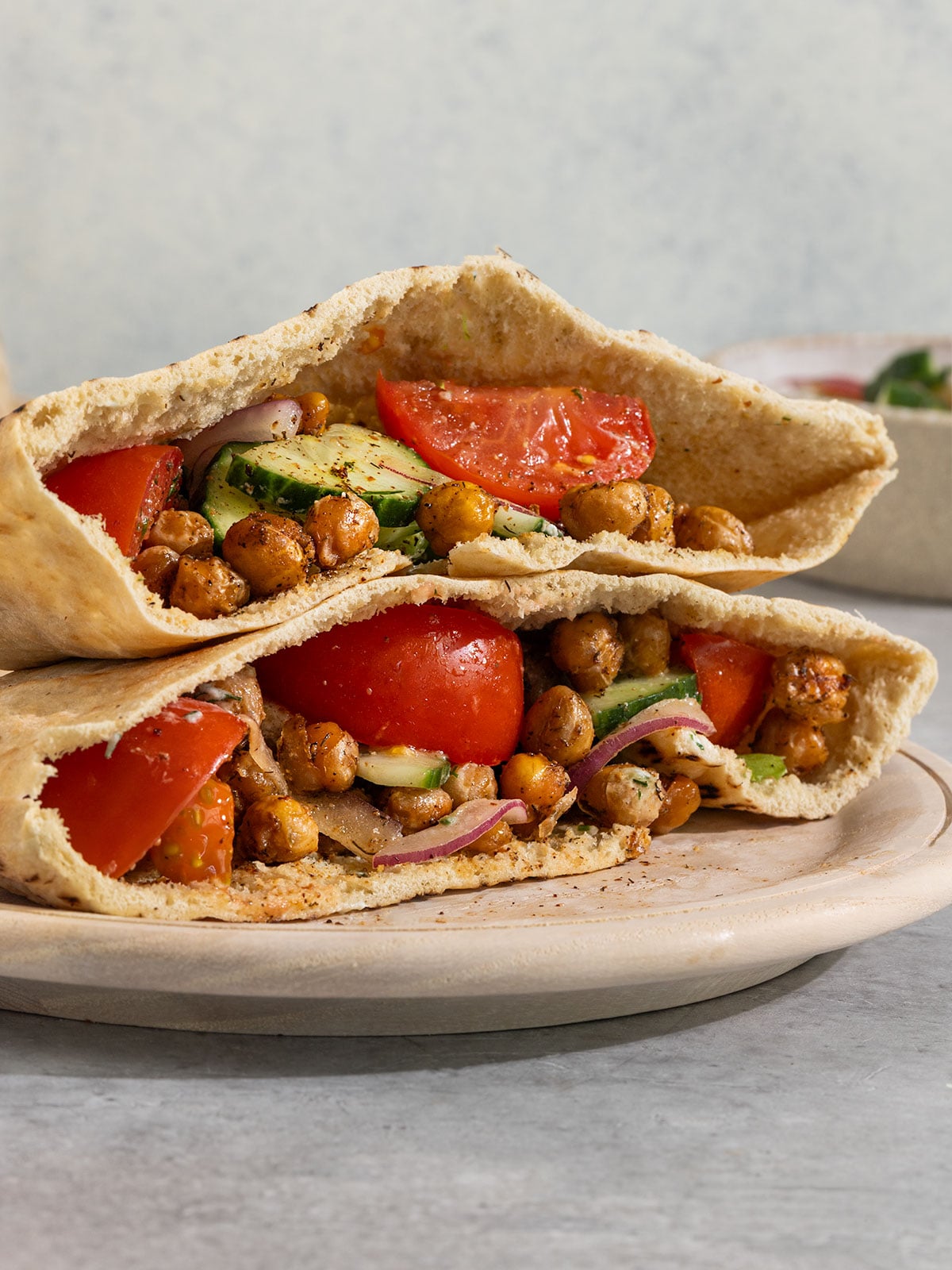 two pita pockets filled with tzatziki, lettuce, tomato, onion, dill, and crispy chickpeas