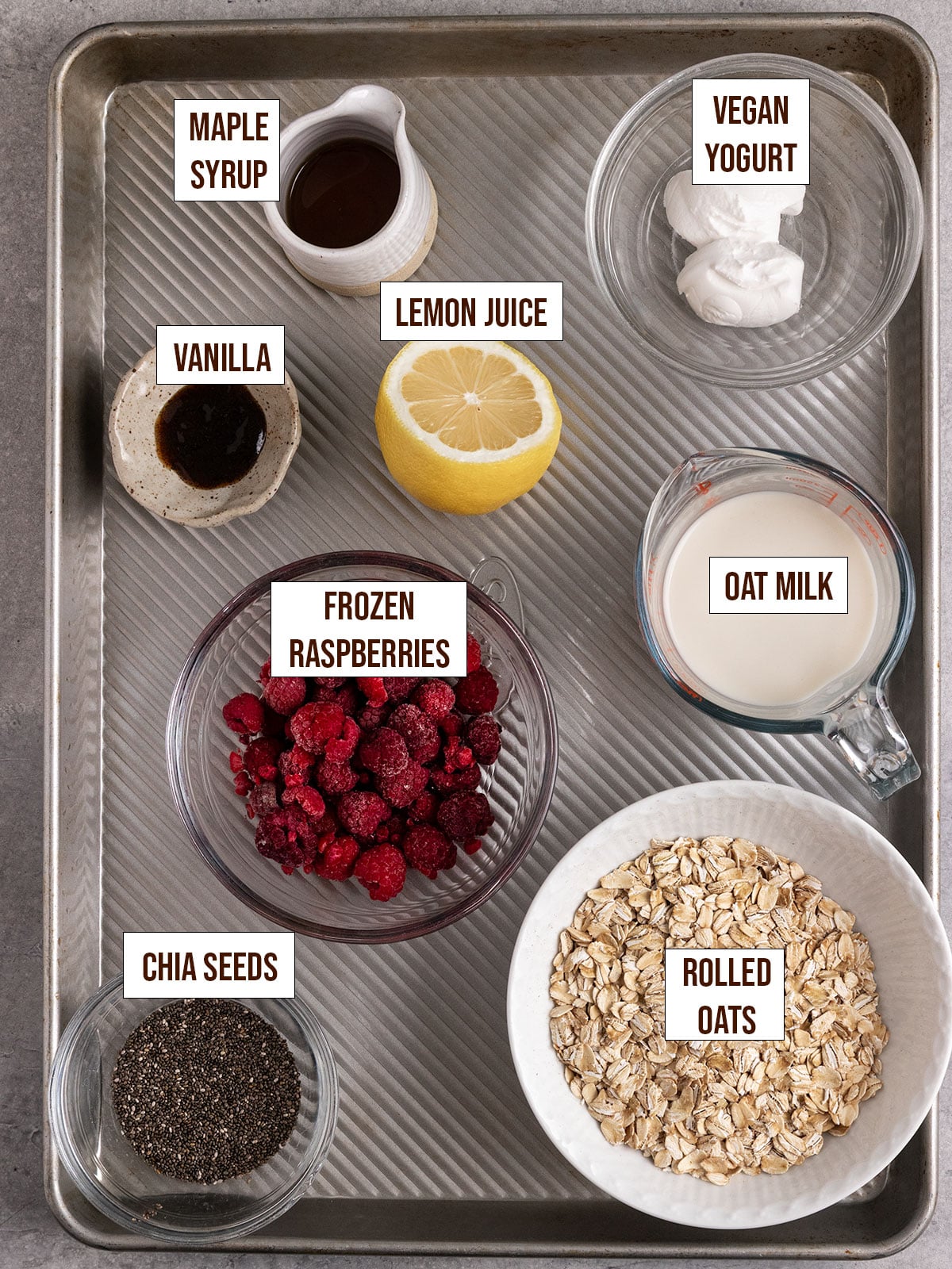 labeled ingredients for raspberry oats including frozen raspberries, oats, vanilla, oat milk, chia seeds, vegan yogurt, maple syrup, and lemon juice.