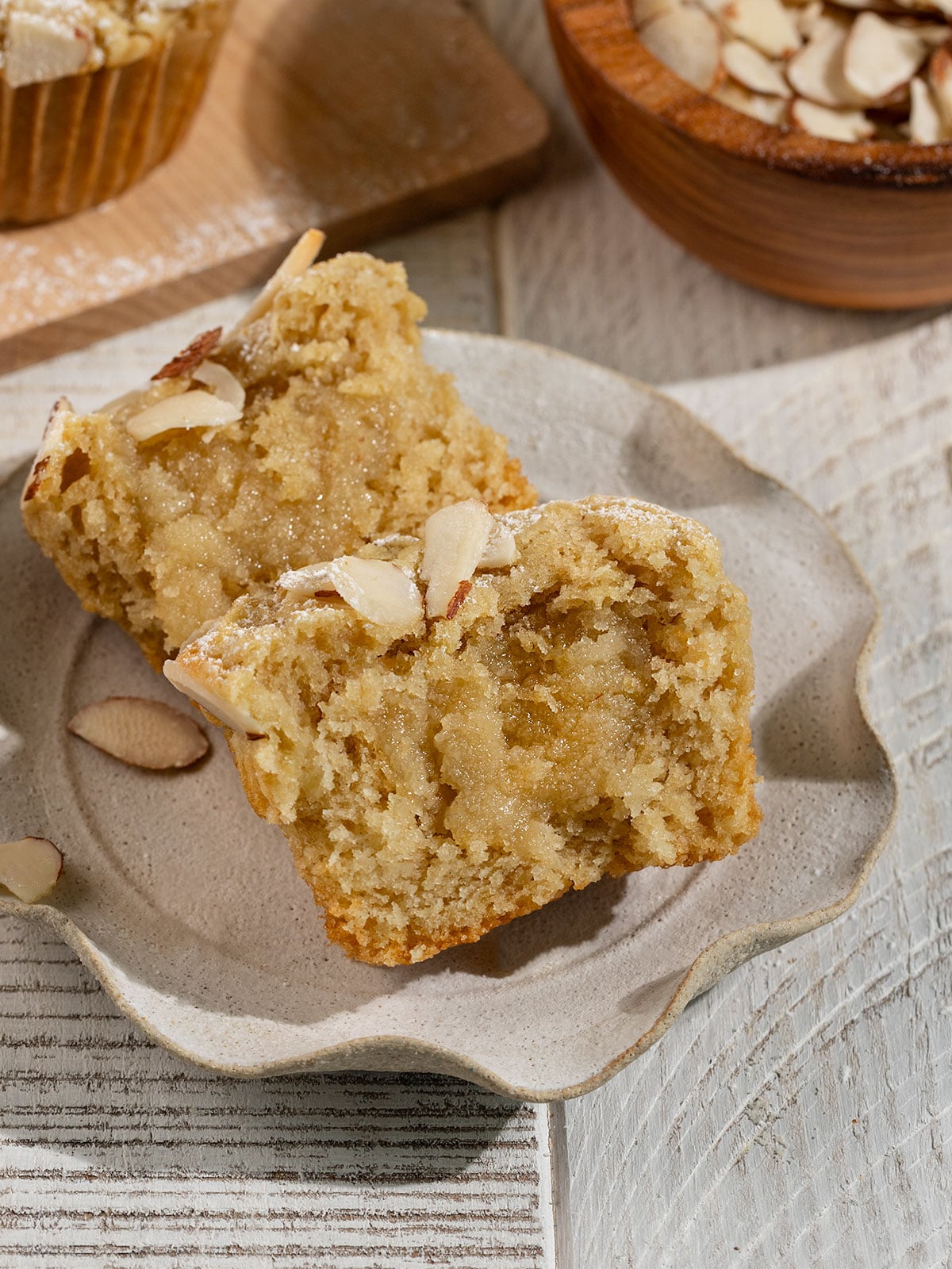 almond muffin on a plate cut in half to show the gooey sugary frangipane in the center.