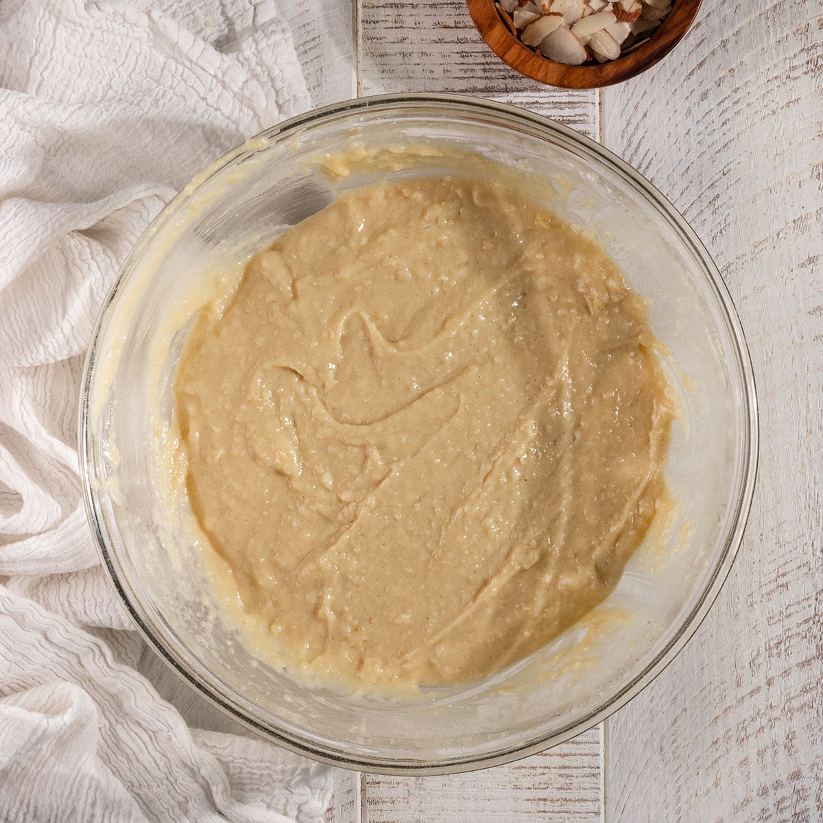 glass bowl filled with almond muffin batter.