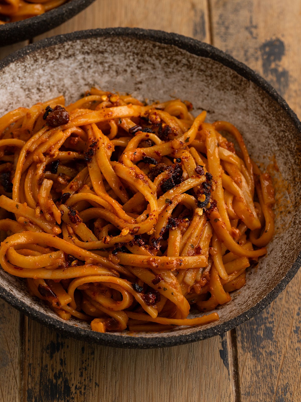 bowl of pasta with tomato chili garlic sauce and more chili oil drizzled on top.