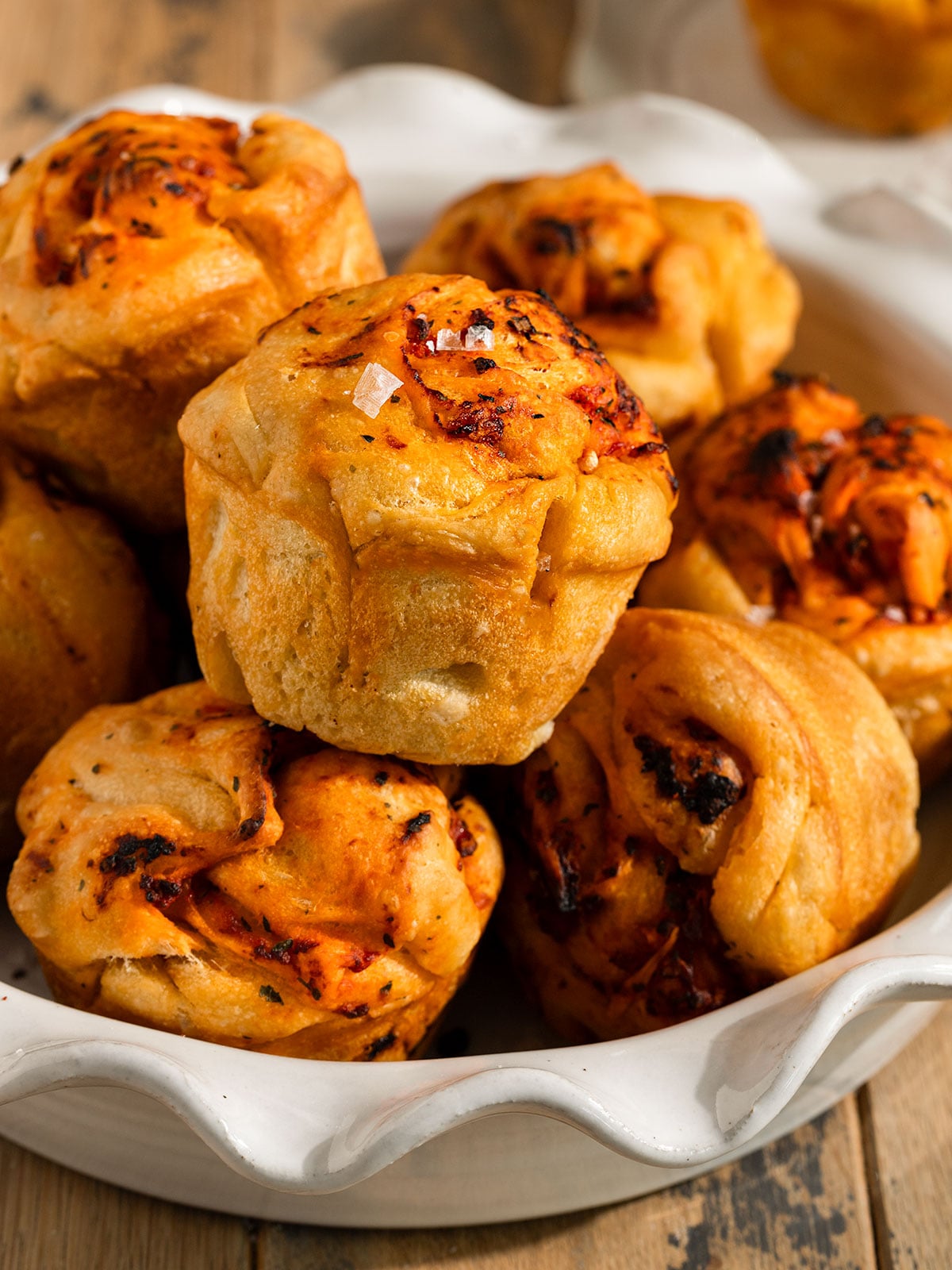 bowl full of stacked focaccia muffins topped with a garlic tomato oil and flaky sea salt.