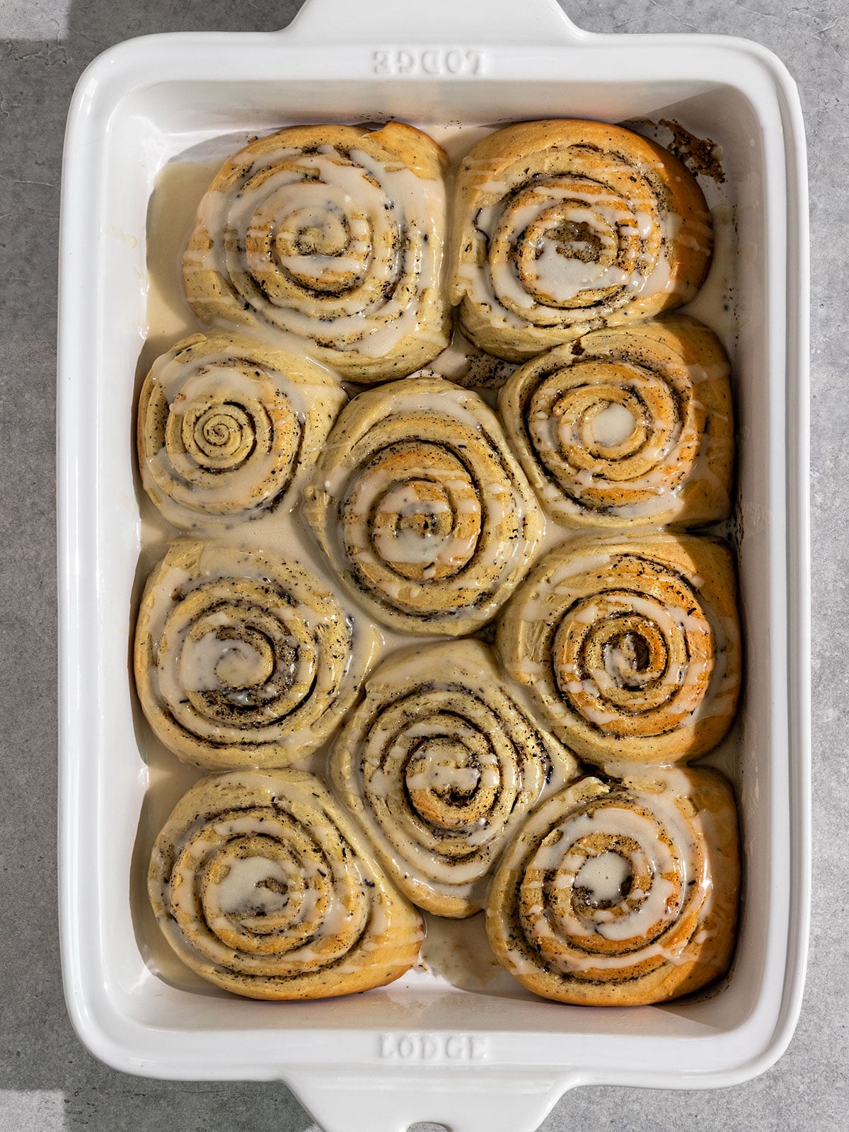 overhead view of earl grey cinnamon rolls in a ceramic pan topped with a lemon icing.