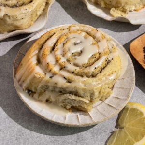 three sweet rolls on plates filled with swirls of earl grey sugar and topped with a lemon icing with lemon slices on side.