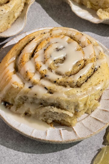 three sweet rolls on plates filled with swirls of earl grey sugar and topped with a lemon icing with lemon slices on side.