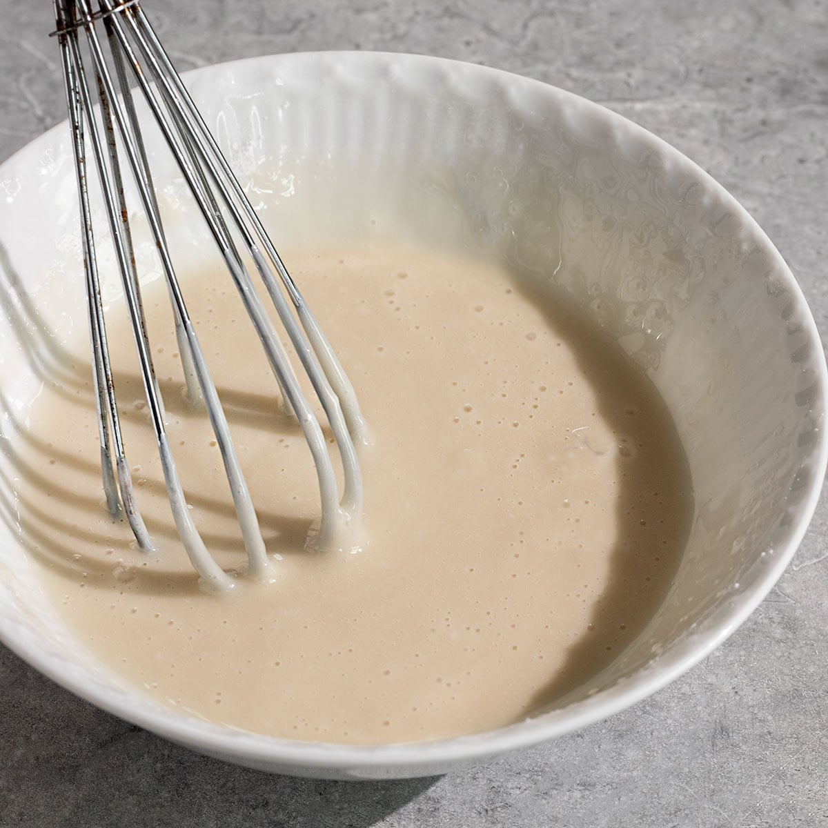 bowl of lemon icing with a whisk in it.