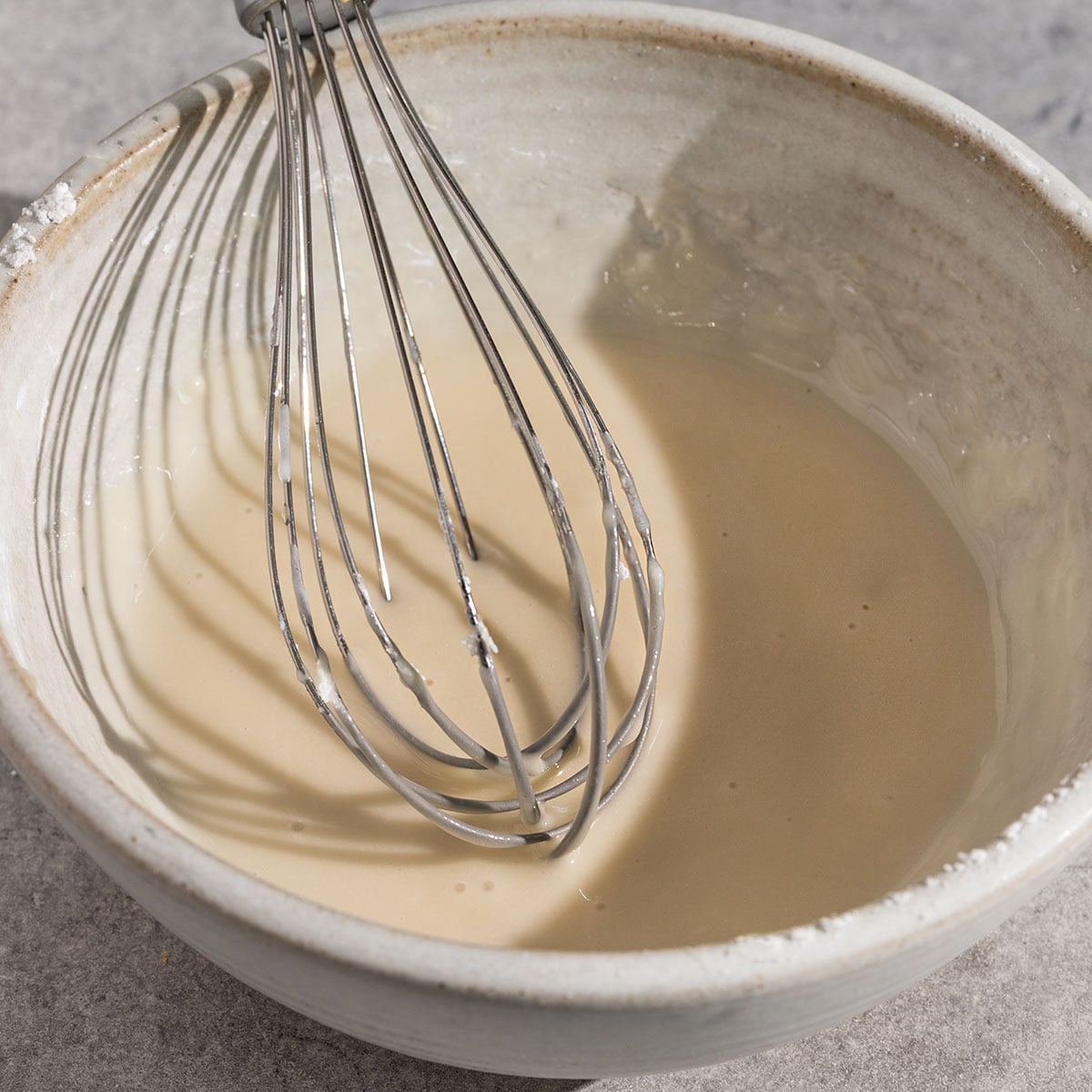 bowl of lemon icing with whisk inside.