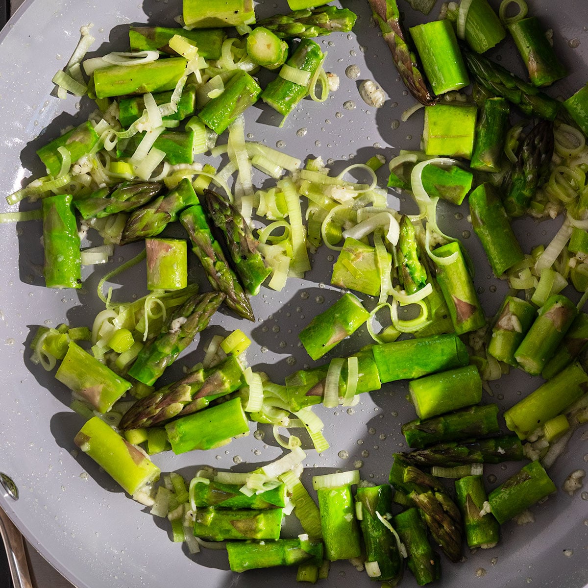 sautéed leeks, asparagus, peas, garlic in a pan.