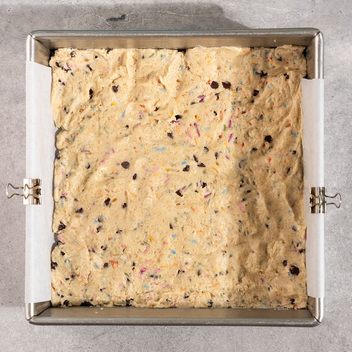 layer of cookie dough pressed into a parchment lined 8 by 8 inch pan.
