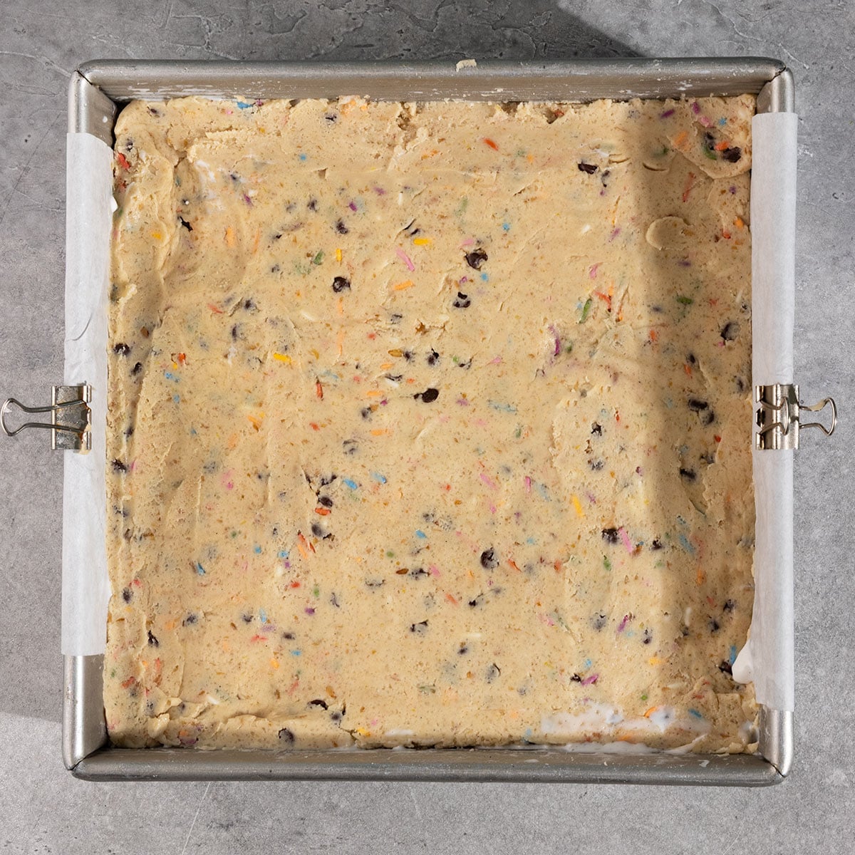 layer of cookie dough pressed into a parchment lined 8 by 8 inch pan.