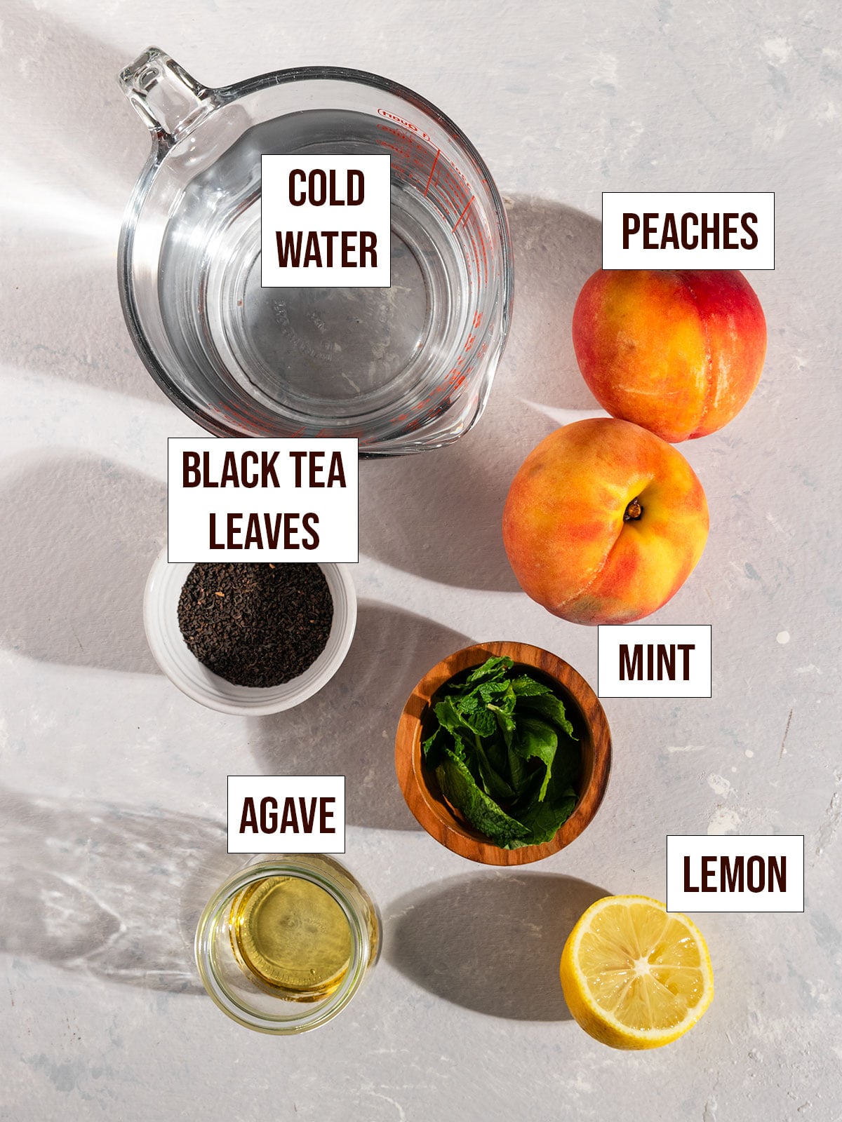 labeled ingredients for peach cold brew including peaches, water, black tea, lemon, mint, and agave.