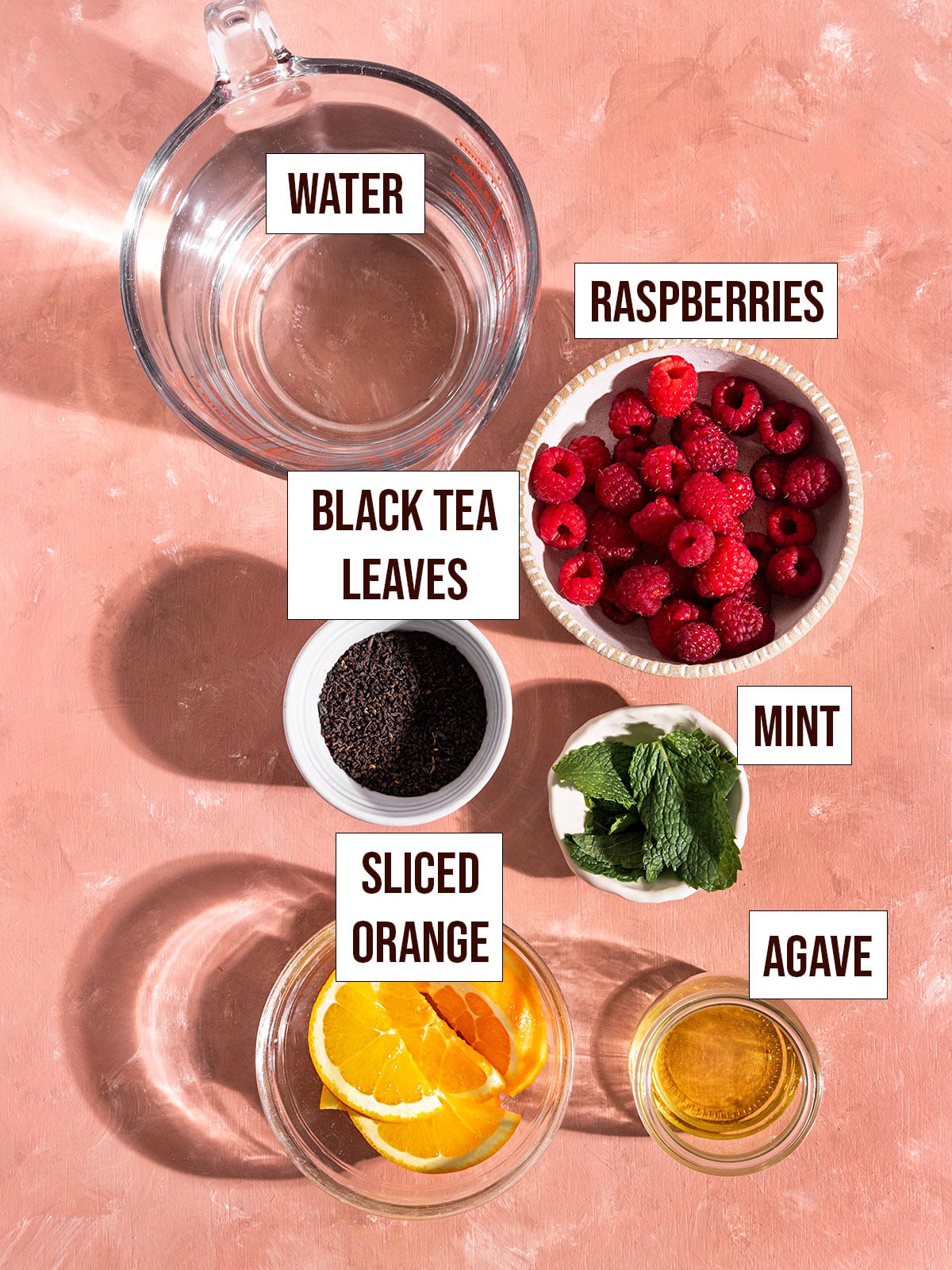 labeled ingredients including water, raspberries, black tea leaves, orange slices, mint, and agave.