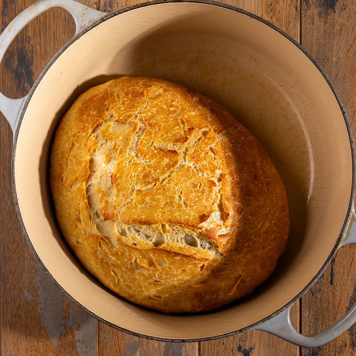 loaf of baked bread with browned crust in a dutch oven.
