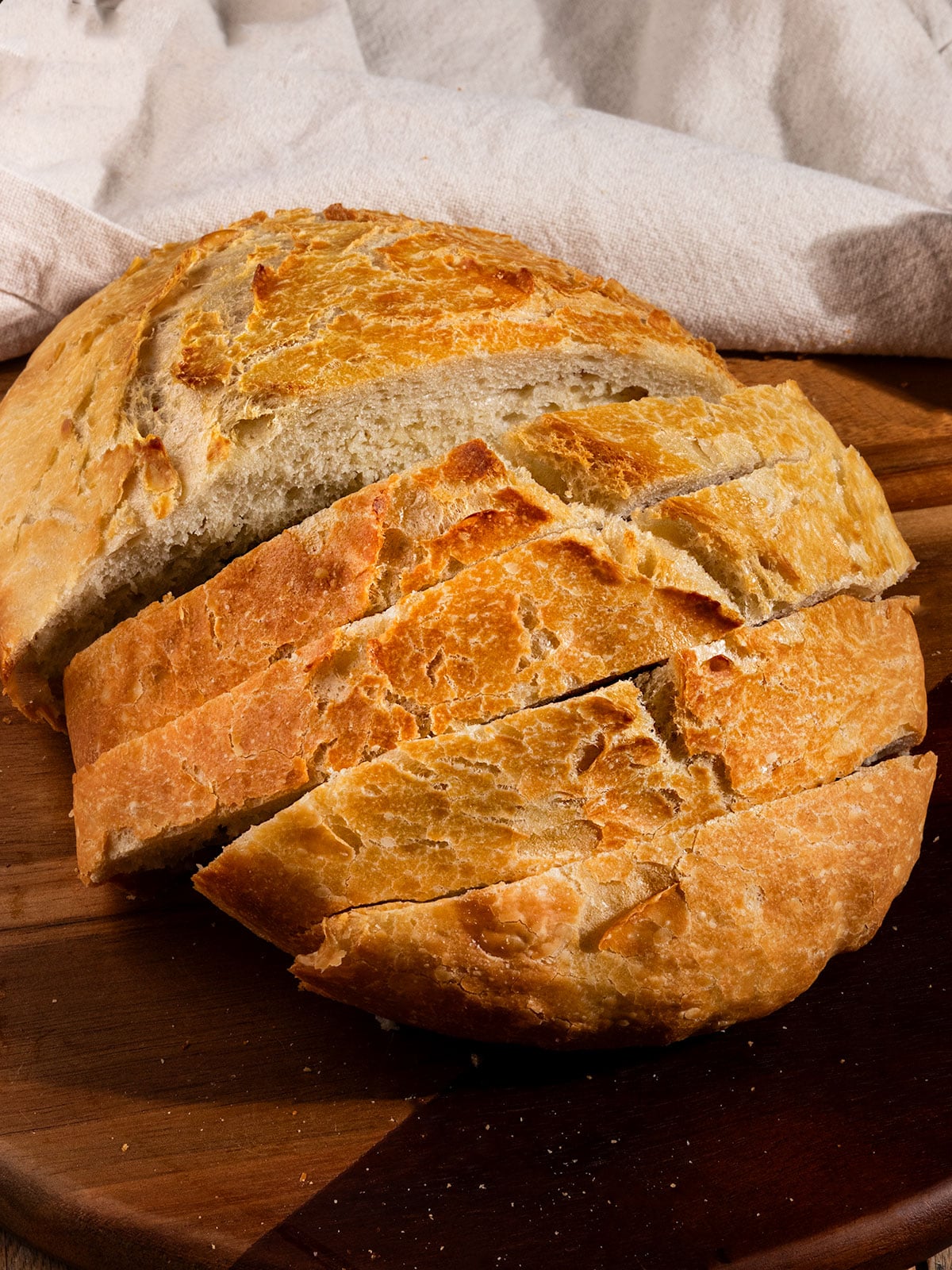 loaf of bread with 4 slices cut out on a wood tray.