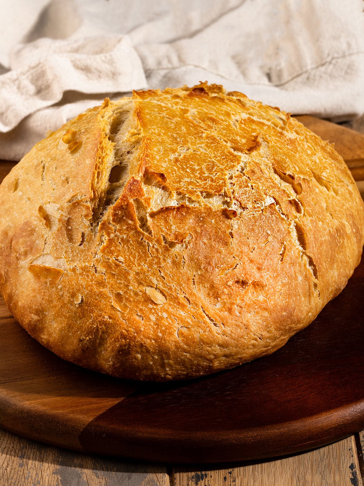 large loaf of rustic bread on a wooden tray.