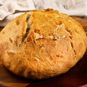 large loaf of rustic bread on a wooden tray.