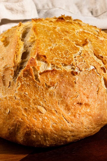 large loaf of rustic bread on a wooden tray.
