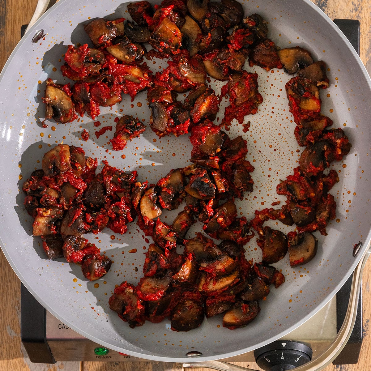 pan with mushrooms and garlic coated in tomato paste and seasoning.