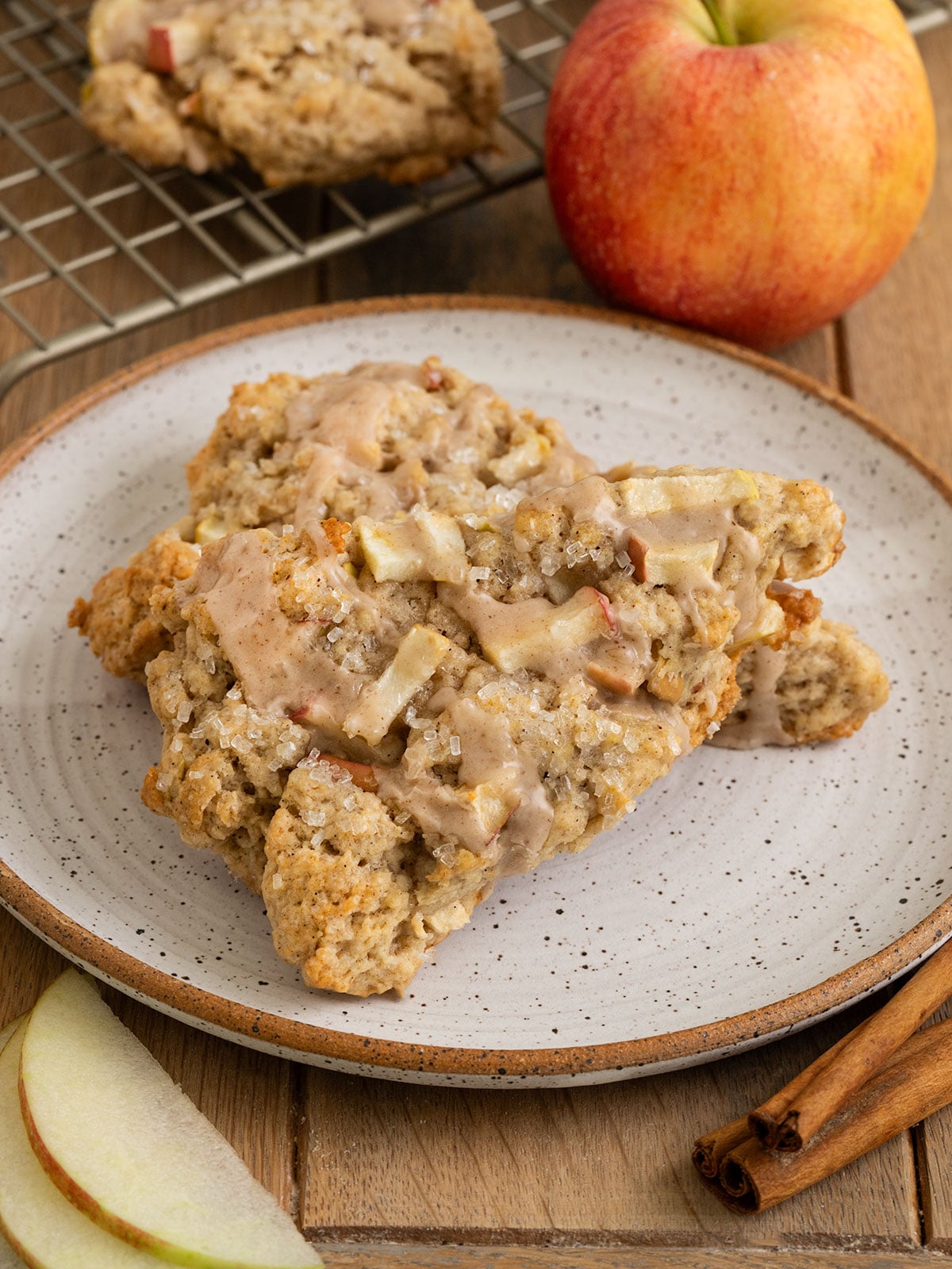 plate with two scones on top of each other filled with chunks of apples and topped with sparkling sugar and an apple spice icing.