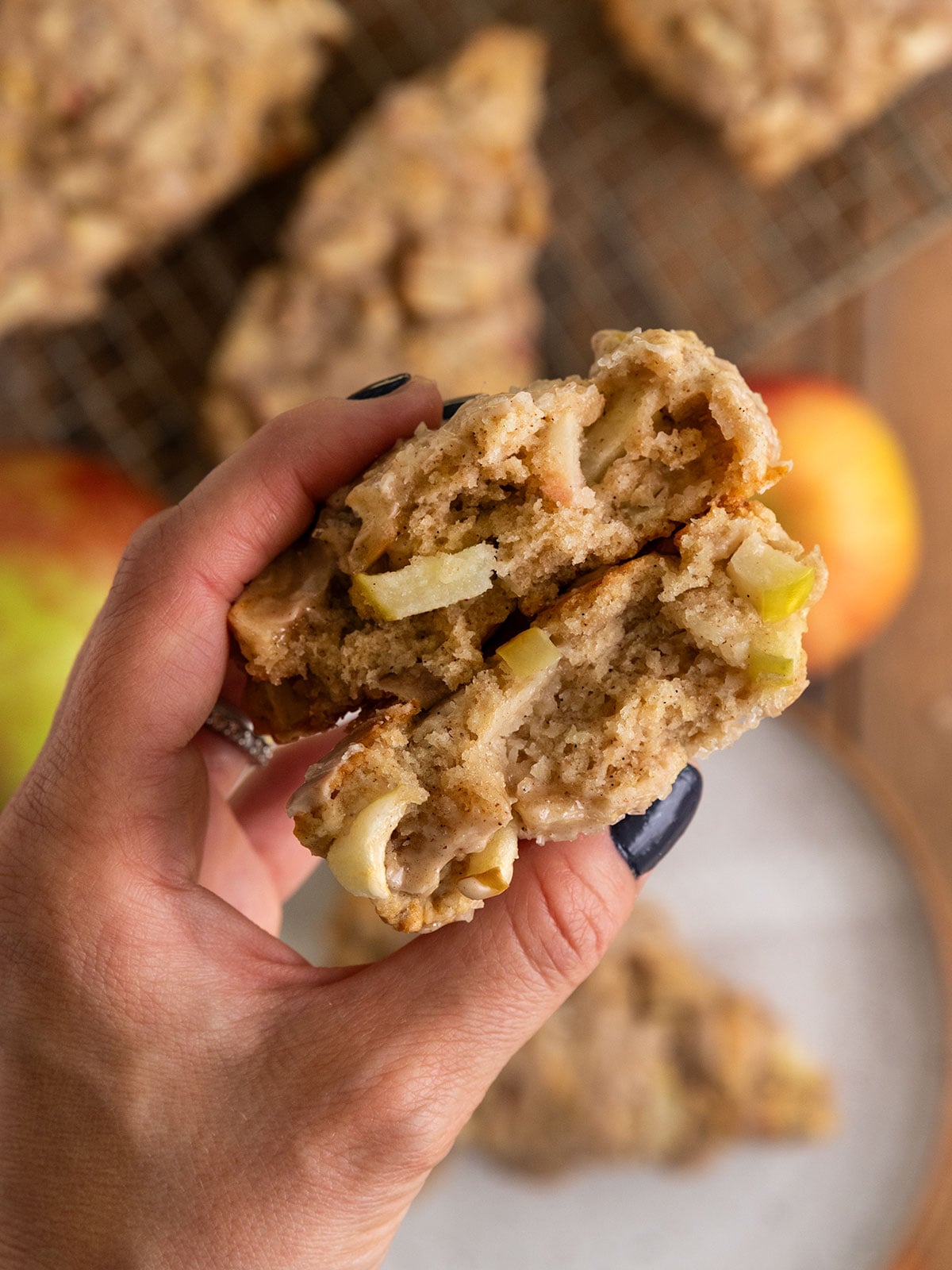 hand holding two pieces of a scone filled with apple chunks.
