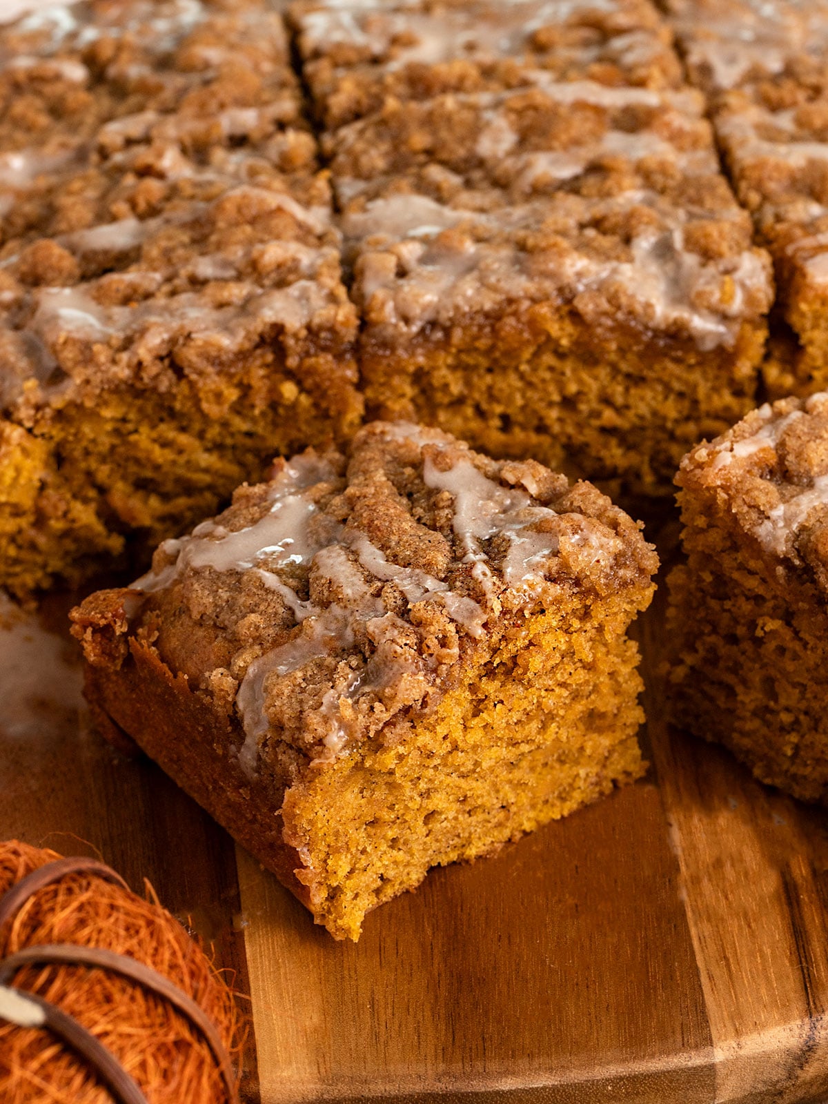 slice of pumpkin cake topped with streusel topping and icing pulled away from cake.