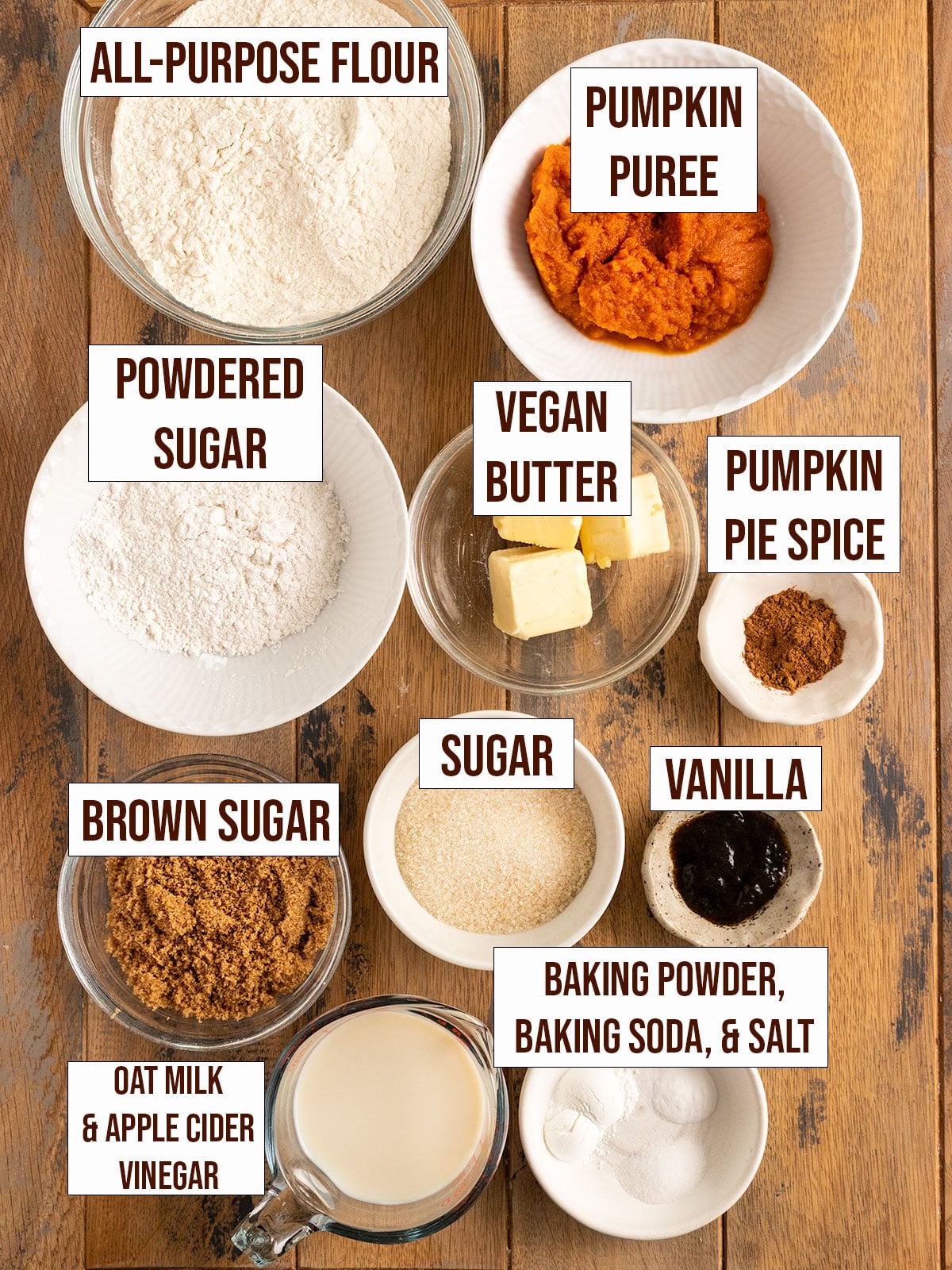 labeled ingredients for pumpkin coffee cake including pumpkin puree, flour, sugar, pumpkin pie spice, vegan butter, baking soda, baking powder, salt, vanilla, apple cider vinegar, and oat milk.