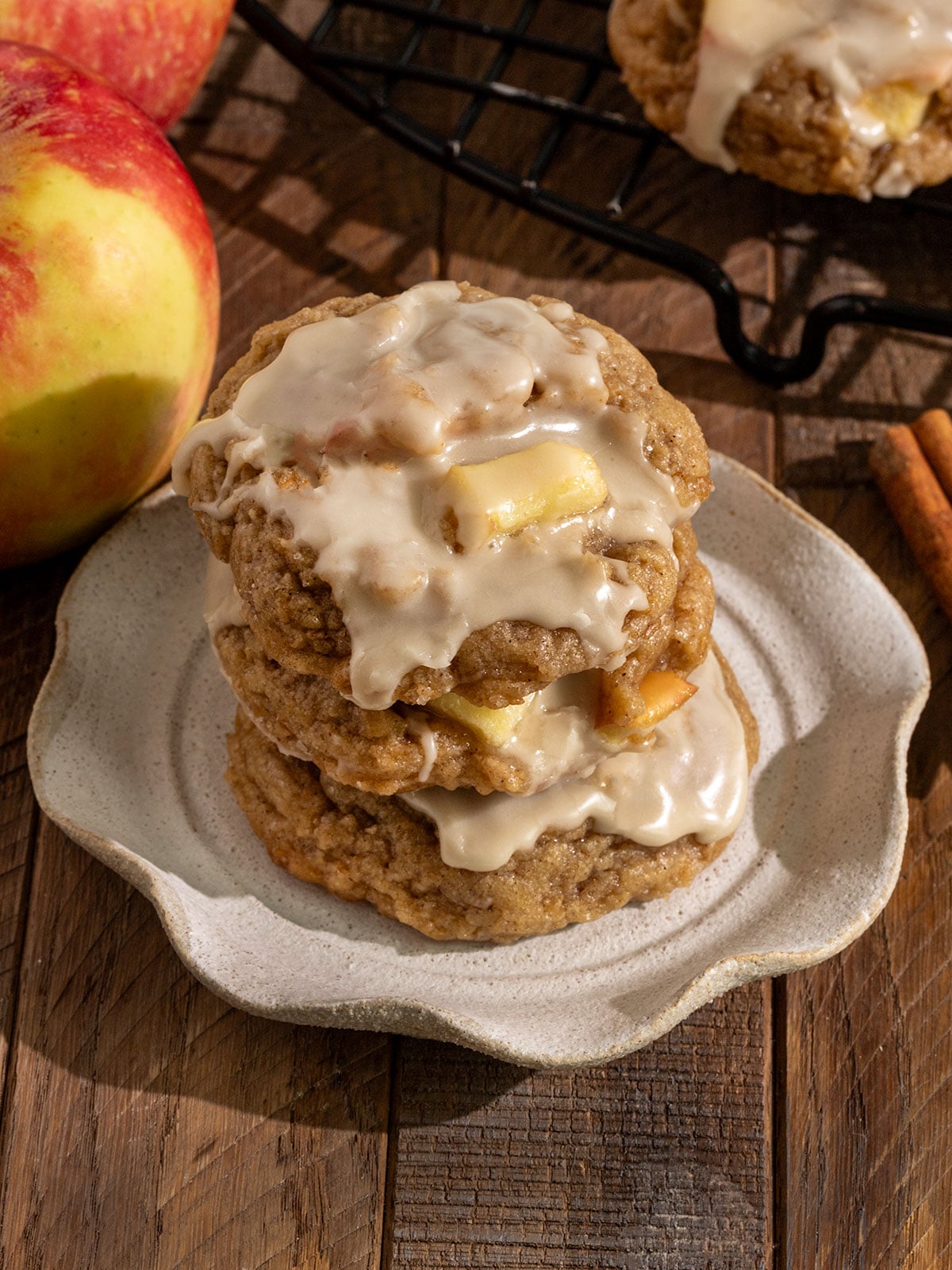 three cookies filled with chunks of apples topped with maple icing stacked onto each other on a fluted plate.
