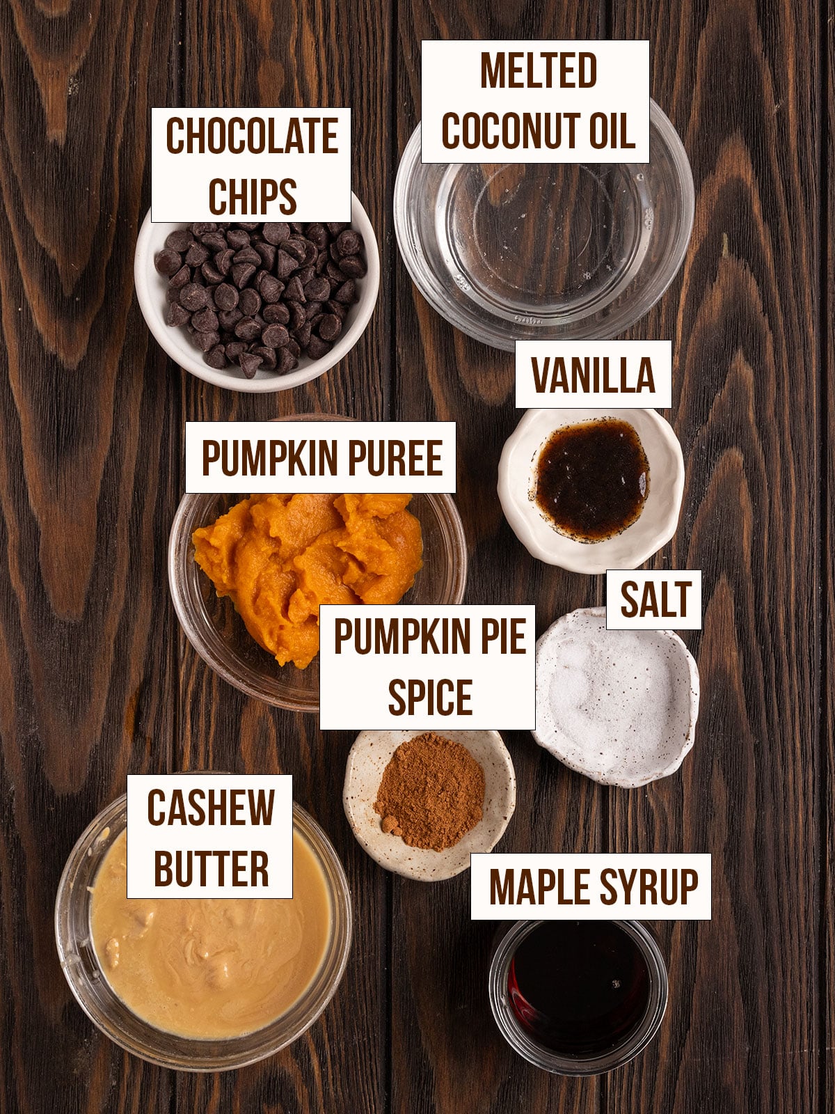labeled ingredients for fudge including pumpkin, cashew butter, maple syrup, coconut oil, vanilla, pumpkin pie spice, salt, and chocolate chips.