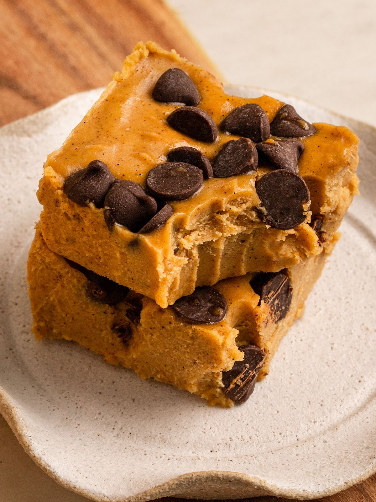 two slices of pumpkin fudge with chocolate chips stacked on a plate with the top square missing a bite.