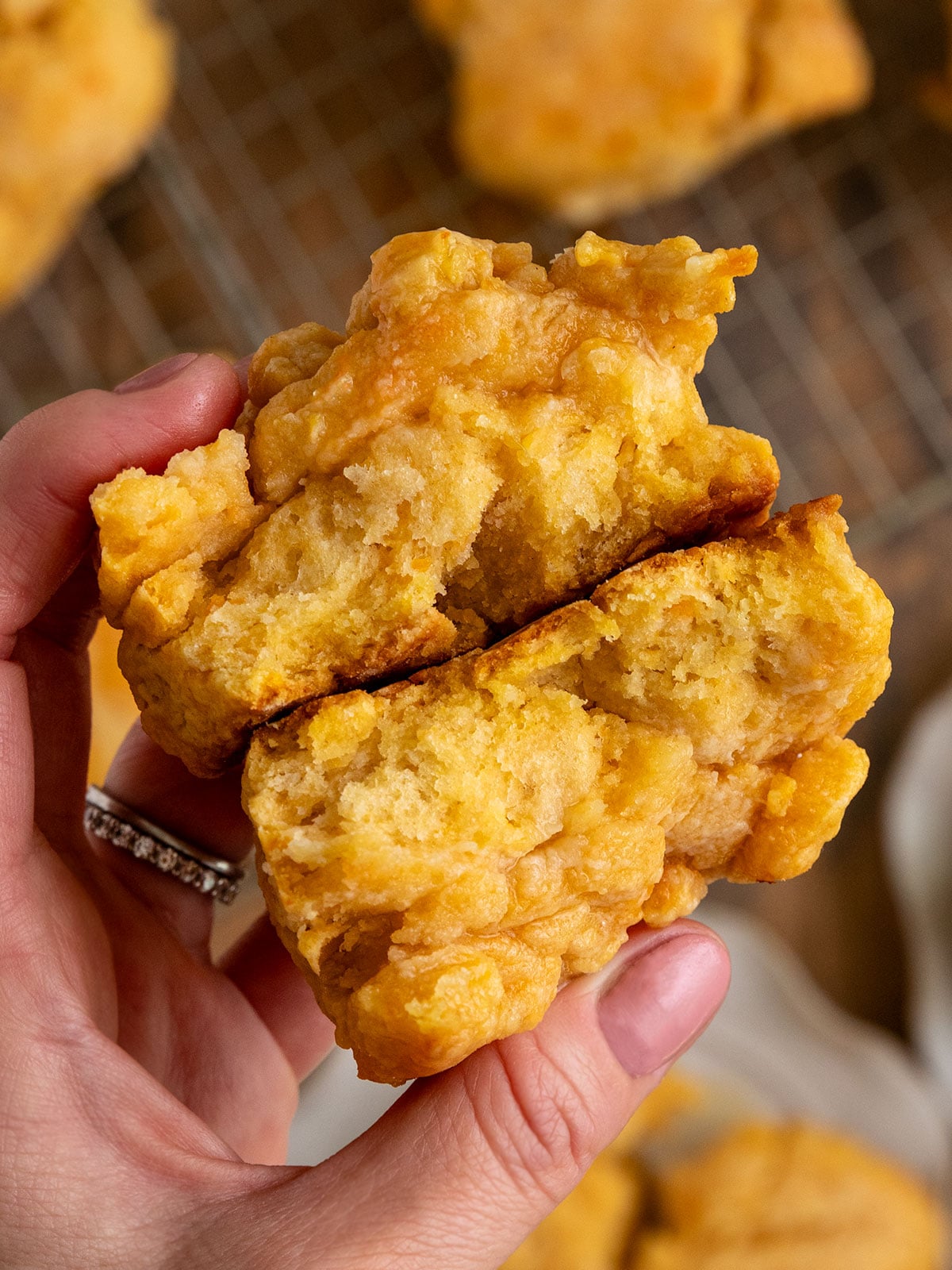 hand holding sweet potato biscuit broken in half to show flaky buttery texture inside.
