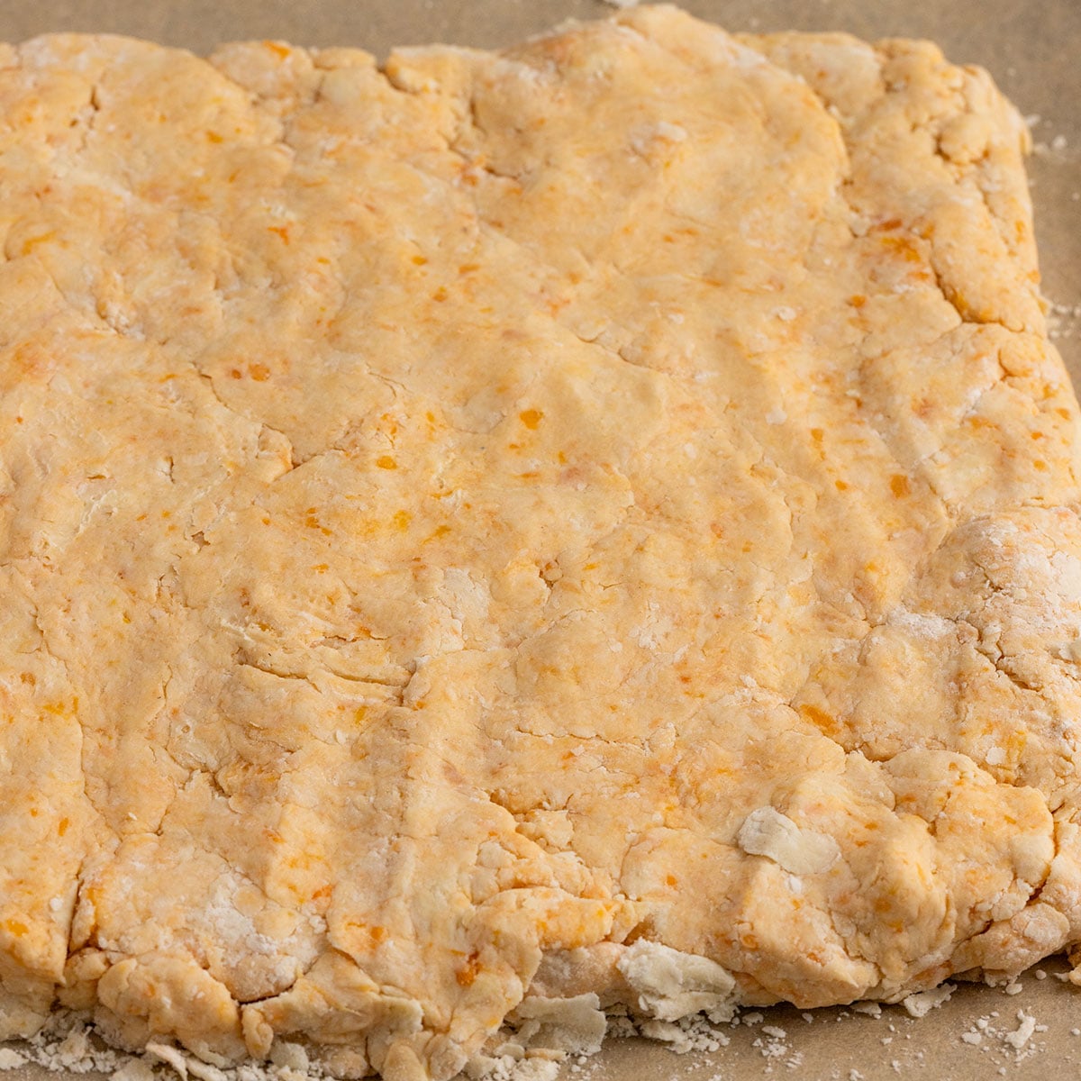 square of sweet potato biscuit dough on a parchment lined baking sheet.